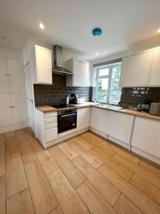 a kitchen with white cabinets and a wooden floor at Groups and Contractors - Newly Renovated 4-bed in Derby