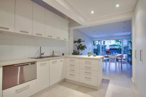 a kitchen with white cabinets and a dining room at 3 Bedrooms - Darling Harbour - Darling St 2 E-Bikes Included in Sydney