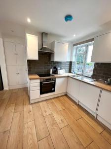 a kitchen with white cabinets and a wooden floor at Groups and Contractors - Newly Renovated 4-bed in Derby