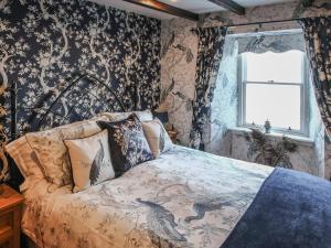 a bedroom with a bed with floral wallpaper at The Moorings in Garlieston