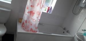 a bathroom with a shower curtain on a tub at Green Village Guest House - Near Manchester Airport in Sale +7 photos