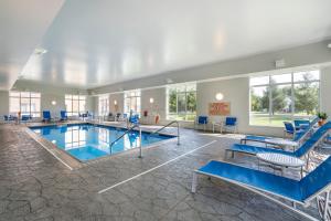 a swimming pool with blue chairs and tables in a building at TownePlace Suites by Marriott Vincennes in Vincennes