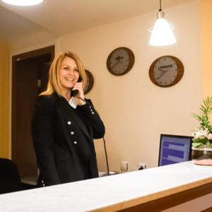 a woman talking on a cell phone in an office with clocks at Hotel Perunika in Golden Sands +13 photos