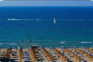 a beach with umbrellas and a sail boat in the ocean at villa aya in Saïdia
