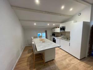 uma cozinha com armários brancos e uma mesa com cadeiras em Duplex sous les toits em Riez