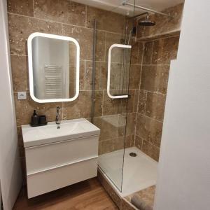 a bathroom with a sink and a shower with a mirror at Duplex sous les toits in Riez