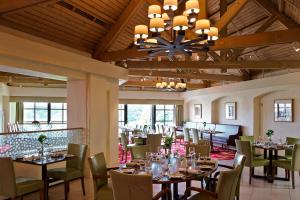 uma sala de jantar com mesas e cadeiras e um lustre em Forest of Arden Hotel and Country Club em Bickenhill