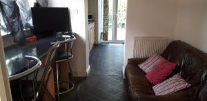 a living room with a couch and a television at Green Village Guest House - Near Manchester Airport in Sale