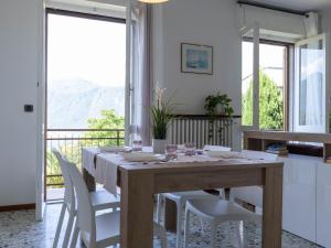 a dining room with a wooden table and white chairs at Mamma Ciccia Holiday Home - Mountains & Lake in Mandello del Lario