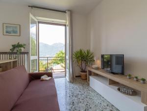 a living room with a couch and a tv at Mamma Ciccia Holiday Home - Mountains & Lake in Mandello del Lario