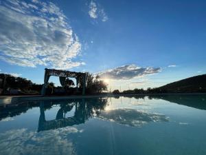 a pool of water with a blue sky and clouds at Cortijo Huerta Galindo in Alanís