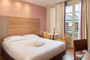 um quarto de hotel com uma cama grande e uma janela em Hôtel de Sévigné em Paris