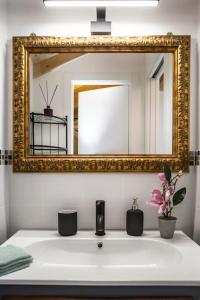 La salle de bains est pourvue d'un lavabo et d'un miroir en or. dans l'établissement La CASETTA Antica dimora nel centro storico, à Chiavari