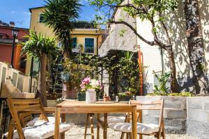 a wooden table and chairs in a courtyard with trees at La CASETTA Antica dimora nel centro storico in Chiavari