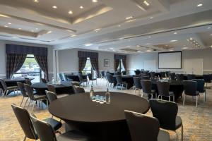 uma sala de conferências com mesas e cadeiras e um ecrã em Delta Hotels by Marriott Northampton em Northampton