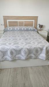 a bedroom with a bed with a gray and white comforter at Apartamentos NayDa N4 de 2 habitaciones in Mérida