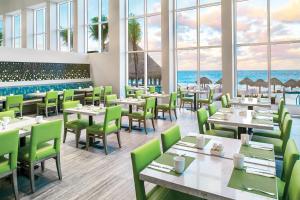 a restaurant with tables and chairs with the ocean in the background at The Westin Resort & Spa Cancun in Cancún