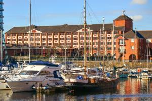 un groupe de bateaux amarrés dans un port avec un grand bâtiment dans l'établissement Delta Hotels by Marriott Swansea, à Swansea