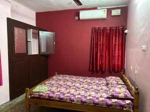 a bedroom with a bed and a red wall at Sowparnika duplex in Trivandrum