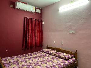 a bedroom with a bed and a window with red curtains at Sowparnika duplex in Trivandrum