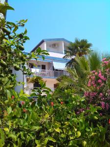 a tall white building with trees and flowers at Apartments Becici in Budva