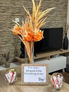 a vase of orange flowers on a table with a sign at Aqua Blue in Ohrid