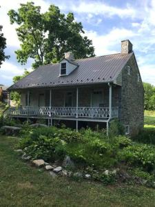 an old brick house with a porch on a field at Springhouse 1803 in Hagerstown