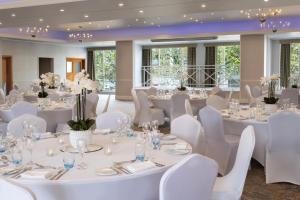 a room filled with white tables and white chairs at Delta Hotels by Marriott Bexleyheath in Bexleyheath