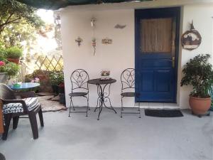 a patio with a blue door and chairs and a table at Ολόκληρο σπίτι in Raches