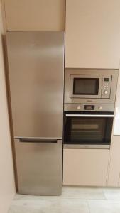 a stainless steel refrigerator and microwave in a kitchen at Casa Jardins da Praia in Póvoa de Varzim