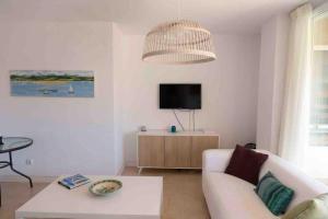 sala de estar con sofá blanco y TV en Gran apartamento, Aire acondicionado, piscina y parking gratuito, en Alicante