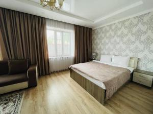 a bedroom with a bed and a chair and a window at Muras in Bokonbayevo