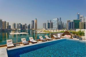a swimming pool with lounge chairs and a city skyline at The St. Regis Downtown Dubai in Dubai