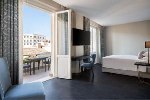 a hotel room with a bed and a desk with a view at Sina Bernini Bristol, Autograph Collection in Rome