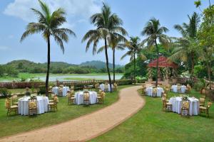 a garden with tables and chairs and palm trees at The Westin Mumbai Powai Lake in Mumbai