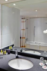 La salle de bains est pourvue de 2 lavabos et d'un grand miroir. dans l'établissement Delta Hotels by Marriott Newcastle Gateshead, à Newcastle upon Tyne