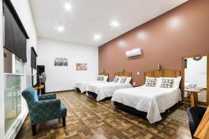 una habitación de hotel con 2 camas y una silla en OYO Hotel Boutique Las Campanas en Tlaxcala de Xicohténcatl