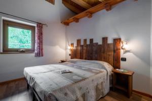 sypialnia z łóżkiem z drewnianym zagłówkiem i oknem w obiekcie Le Vieux Noyer - Appartamenti al Verde villaggio di Rumiod w mieście Saint-Pierre