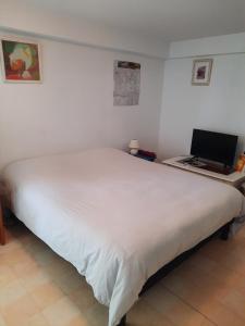 1 dormitorio con 1 cama blanca y escritorio con ordenador portátil en Les coteaux de Planèze, chambre pour 2, 3 ou famille nombreuse 2 adultes 5 enfants et jeunes, en Belmont-Bretenoux