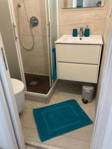 een badkamer met een wastafel, een douche en een blauw tapijt bij Superbe studio au cœur de Nice ! in Nice