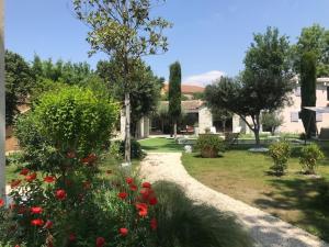 a house with a garden with flowers and trees at La Maison 1440 in L'Isle-sur-la-Sorgue
