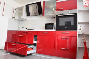 Appartement Bühelblick في غاسشرن: مطبخ احمر مع دواليب حمراء وميكرويف