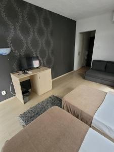 a bedroom with a bed and a tv and a couch at Guest House Taligarov in Pomorie