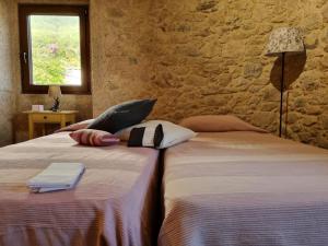 two beds in a room with a stone wall at Alojamiento Casa Carlota in Villadesuso
