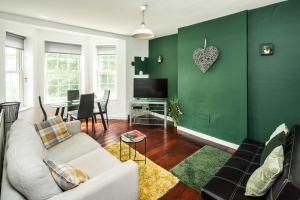 a living room with a white couch and a green wall at Cosy 3BD London accommodation for 6 / 6 beds in London