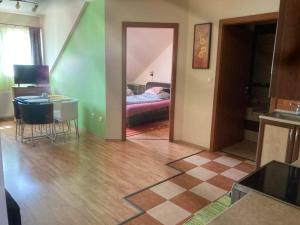 a room with a kitchen and a room with a bed at Árnyas Residence Apartman Pécs in Pécs