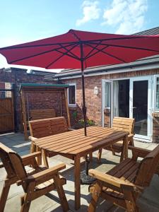 a wooden picnic table with an umbrella on a patio at Strawberry Fields in Cockermouth