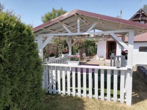 a white wooden pergola with a white fence at Mały Biały Domek in Pobierowo
