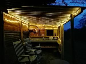 a kitchen with chairs under a pergola with lights at Penn Bergeyn Shepherd's Huts in Exeter