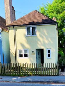 a small white house with a wooden fence at 3-bed cottage in Sway, New Forest (5 min walk from Sway Train Station) in Sway